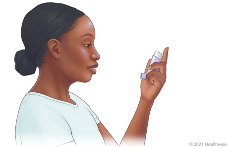 Person holding inhaler upright, with mouthpiece on bottom facing mouth. Person holding inhaler upright, with mouthpiece on bottom facing mouth.