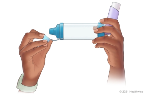 Person removing cap from end of inhaler opposite where inhaler was inserted. Person removing cap from end of inhaler opposite where inhaler was inserted.