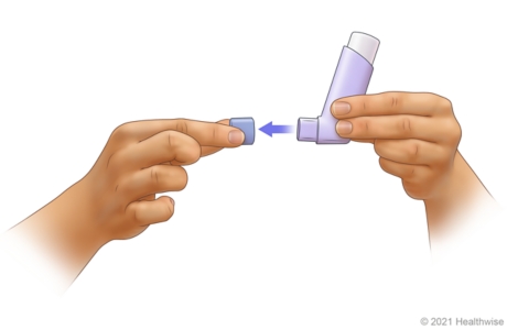 Removing cap from mouthpiece of inhaler. Removing cap from mouthpiece of inhaler.