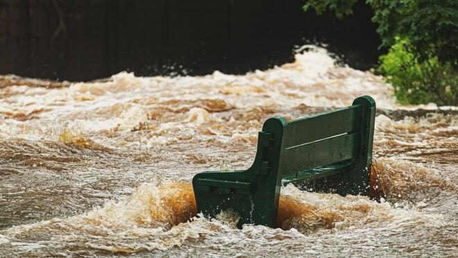 Flood waters surround a green bench