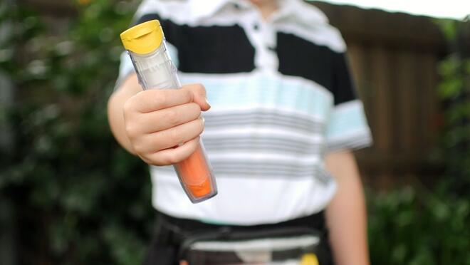 Close up of child holding epi pen
